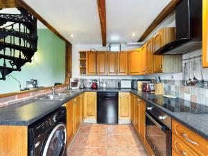 a kitchen with wooden cabinets and a black dishwasher at The Old Coach House in Iddesleigh