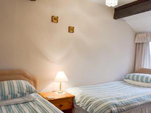 a bedroom with two beds and a lamp on a table at Ash Cottage in Tarvin