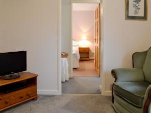 1 dormitorio y sala de estar con TV y silla. en Ash Cottage, en Tarvin