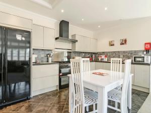 a white kitchen with a white table and chairs at Owls Croft - 27898 in Broadstairs