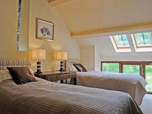 a bedroom with two beds and a desk and windows at Hendre Barn Mawr in Abergynolwyn