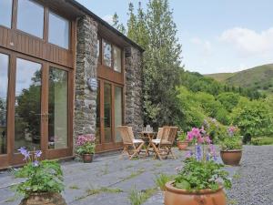 a stone house with a patio with chairs and flowers at Hendre Barn Mawr in Abergynolwyn