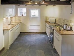 a kitchen with white cabinets and a sink at Sharrowhead Cottage - E4044 in Robin Hood's Bay