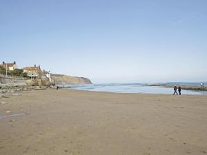 a beach with people walking on the sand at Sharrowhead Cottage - E4044 in Robin Hood's Bay