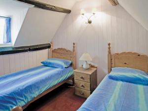 a bedroom with two beds and a table with a lamp at Sharrowhead Cottage - E4044 in Robin Hood's Bay