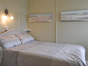 a bedroom with a bed with two pictures on the wall at Polmeor in Polzeath