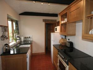 クロムフォードにあるThe Secret Cottageのキッチン(木製キャビネット、白い冷蔵庫付)