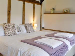 a bedroom with a white bed with towels on it at Churchill Cottage in Holwell