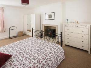 a bedroom with a bed and a dresser and a fireplace at Barbican Cottage in Middleham