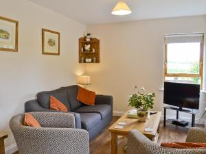 a living room with a couch and a tv at Chestnut Cottage-27565 in Botesdale
