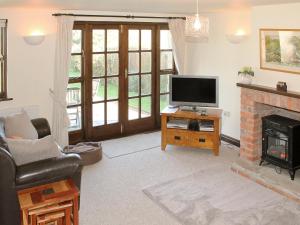 a living room with a tv and a fireplace at Swallow Cottage in Shanklin