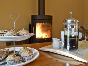 a table with cupcakes and a stove with a fireplace at The Stables- Osb in Penbryn