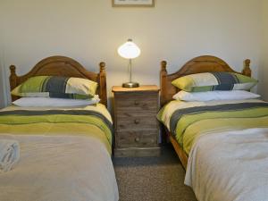 a bedroom with two beds and a lamp on a night stand at Ty Hen in Llangwnadl