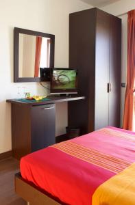 Schlafzimmer mit einem Bett und einem TV auf einem Schreibtisch in der Unterkunft Nacional B&B in Monforte San Giorgio Marina