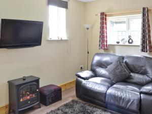 a living room with a leather couch and a stove at Fir Tree Cottage - Ukc646 in Byrness