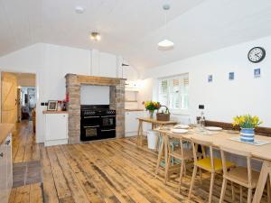 a kitchen with white walls and wooden floors at Ty Cai in Llanwnda