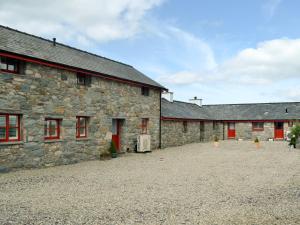 two stone buildings with red doors and a courtyard at Ty Cai in Llanwnda