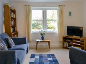 a living room with a blue couch and a tv at 11 Elm Court in Keswick