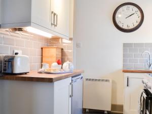 a kitchen with a counter and a clock on the wall at St Cadoc Cottage in Saint Merryn