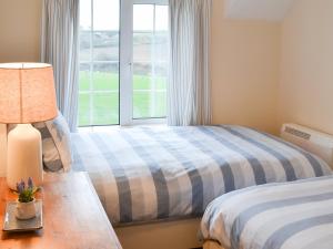 1 dormitorio con 2 camas y ventana en St Cadoc Cottage, en St Merryn