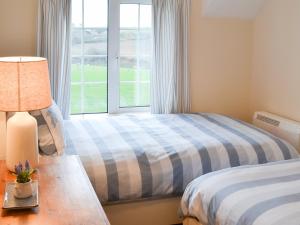 a bedroom with two beds and a window at St Cadoc Cottage in Saint Merryn