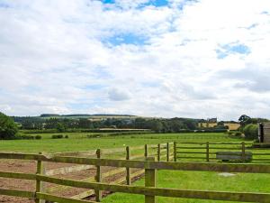 a wooden fence in a field with green grass at Stable Cottage in Burythorpe