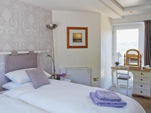 a bedroom with a white bed and a window at Appleshine Cottage in Almondbury