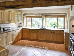 a kitchen with wooden cabinets and a large window at Lee Cottage in Heptonstall