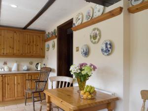 a kitchen with a wooden table and plates on the wall at Tillet Cottage in Flixton