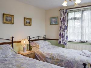 a bedroom with two beds and a window at Tillet Cottage in Flixton