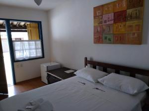 a bedroom with a white bed and a window at Pousada Amaryllis in Tiradentes