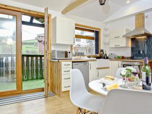 a kitchen with white cabinets and a table with chairs at Hunters Lodge in Kingskerswell