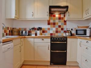 a kitchen with white cabinets and a black oven at Rathlin Coach House in Comrie