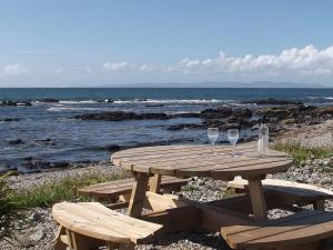 a picnic table with two wine glasses on the beach at Shore Cottage in Bellochantuy