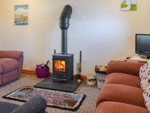 a living room with a wood stove in a living room at Stonefold Cottage in Waberthwaite