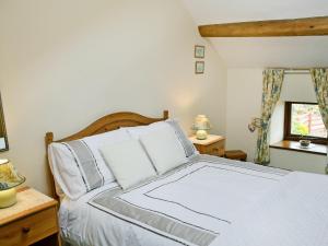 a bedroom with a bed with white sheets and a window at Stonefold Cottage in Waberthwaite