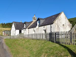 an old white building with a wooden fence at Kates Croft in Portgower