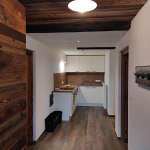Il comprend une cuisine avec des placards blancs et un plafond en bois. dans l'établissement Appartements Steffila, à Sand in Taufers