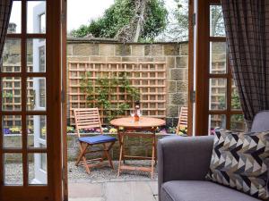 patio con mesa, sillas y ventana en Vanehouse Apartment en Osmotherley