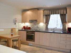 una cocina con armarios de madera, mesa y fregadero en Vanehouse Apartment en Osmotherley