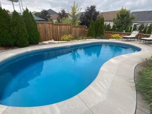 een groot blauw zwembad in een tuin bij Living the Dream with Inground Heated Pool, Hot Tub, & Beach in Cobourg