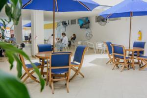 un comedor con sillas azules, mesas y sombrillas en Hotel Neiva Plaza, en Neiva
