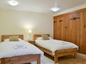 a bedroom with two beds and wooden cabinets at Tythe Barn in Froggatt
