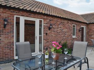 a glass table with wine glasses and flowers on a patio at The Old Dairy in Normanton on Trent