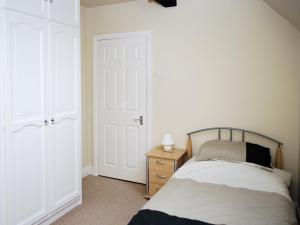 ein Schlafzimmer mit einem Bett, einer Kommode und einer Tür in der Unterkunft The Old School House in Tideswell
