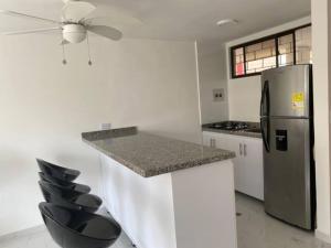 cocina con encimera, nevera y sillas en Apartamento Tacoa 703, en Santa Marta