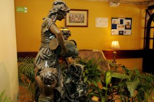a statue of a woman and a child in a living room at Colony Inn Hotel in Ambato