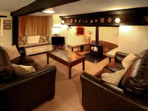 a living room with leather furniture and a fireplace at Oddwell Cottage in Brompton Ralph