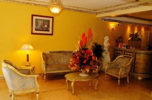 sala de estar con sofá y mesa con un jarrón de flores en Colony Inn Hotel, en Ambato