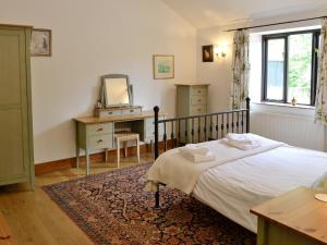 1 dormitorio con cama, escritorio y espejo en Woodpecker Cottage, en Haydon